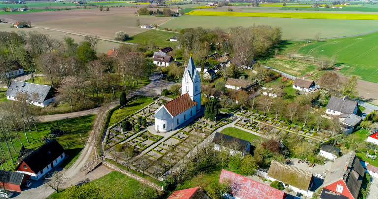 Flygbild över Äspö kyrka med omgivande bebyggelse.