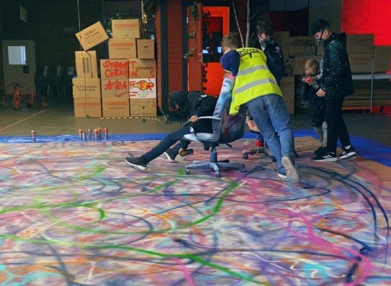 ungdomar som kör en kontorsstol och sprejar färg