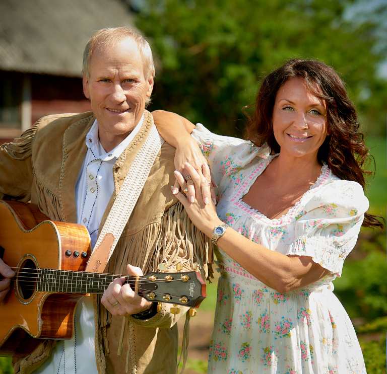 Man med gitarr och kvinna som lutar sig mot mannens axel.