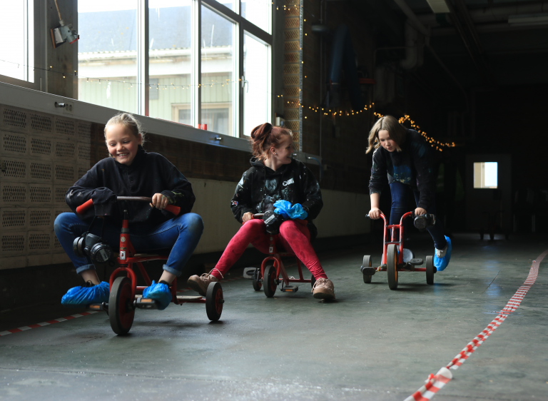 Ungdomar cyklar på barncyklar inomhus