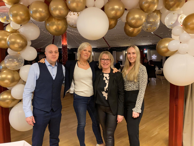 Fyra personer står inramade av ballonger i olika färger.