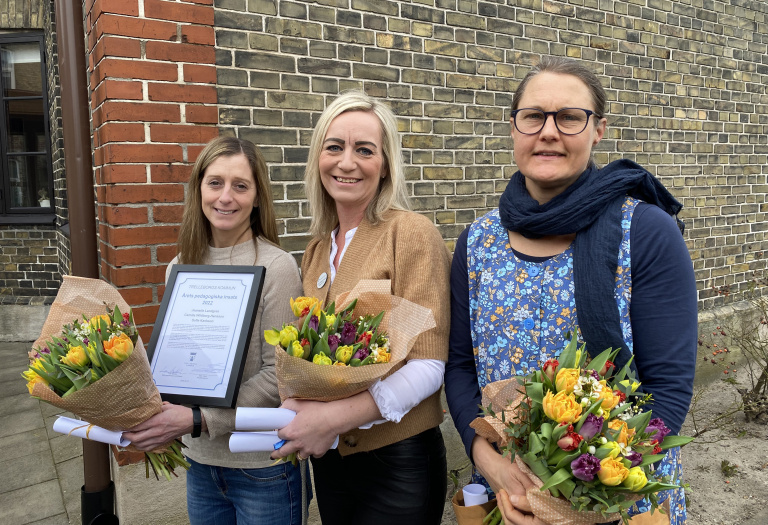 Tre kvinnor med blommor och diplom.