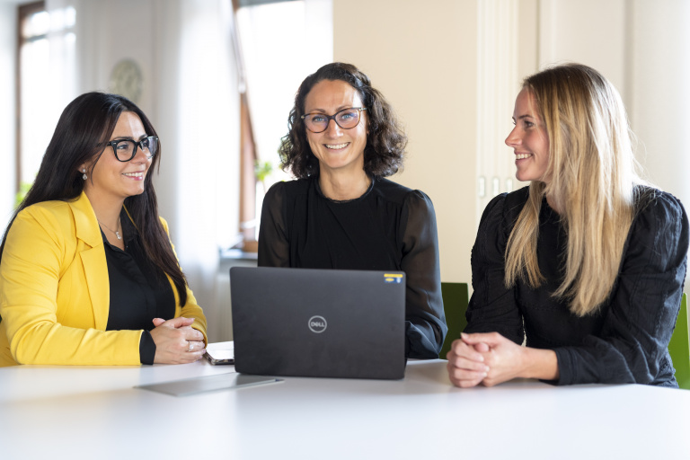 Layal Chidiac, Caroline Abraham och Helena Helldal sitter vid ett bord med en bärbar dator framför sig.