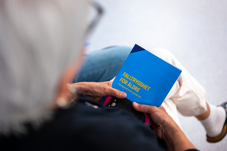 Kvinna sitter med folder i knät.