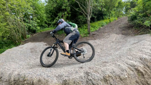 Man cyklar på bana i skogsområde