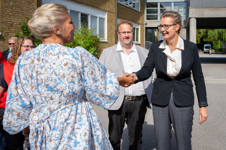 Två kvinnor skakar hand på skolgård