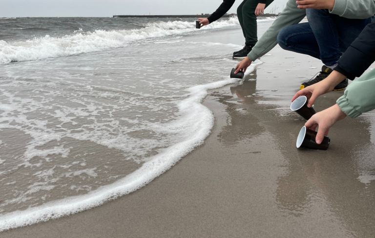 Händer vid vattenbryn på strand