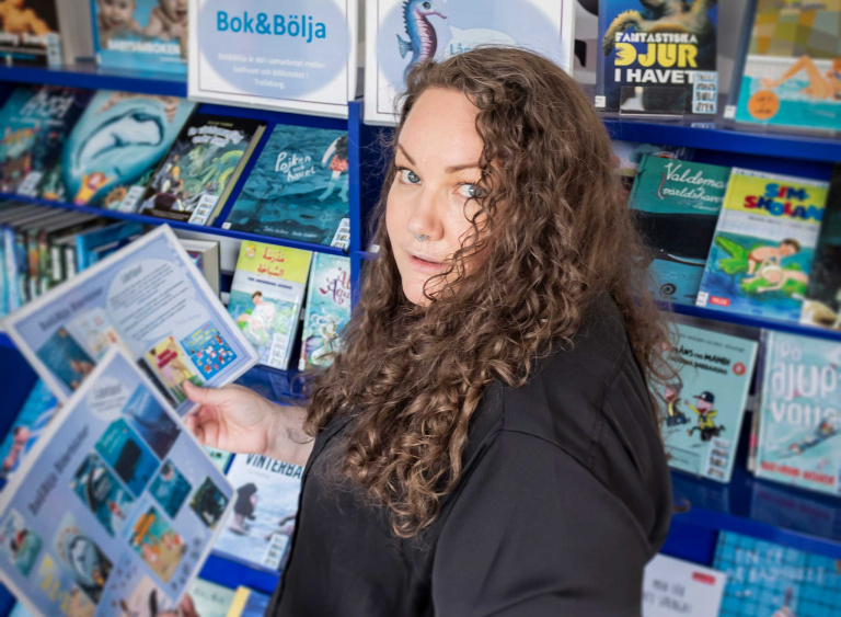 Kvinna med folder vid bokhylla