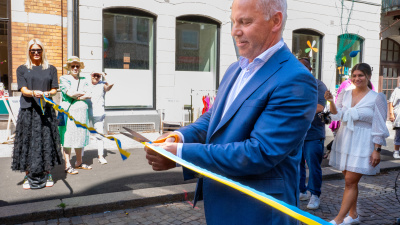 Man i kostym som klipper ett gult och blått band