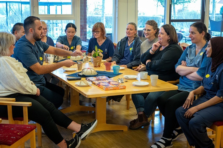 Personalgrupp sitter vid bord och äter tårta.