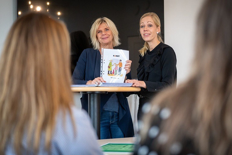 Två kvinnor presenterar föräldramaterial för gruppdeltagare.