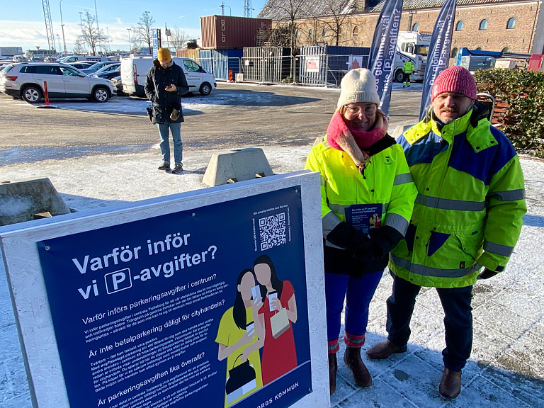 Två personer i gula jackor vid trottoarpratare