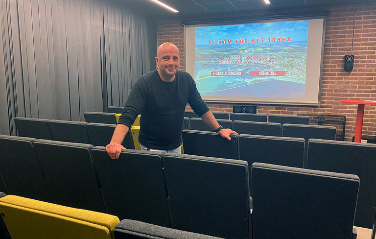 man i bänkrad framför tv-skärm