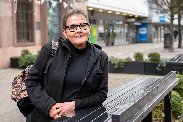 Kvinna står utomhus lutad mot ett bord.