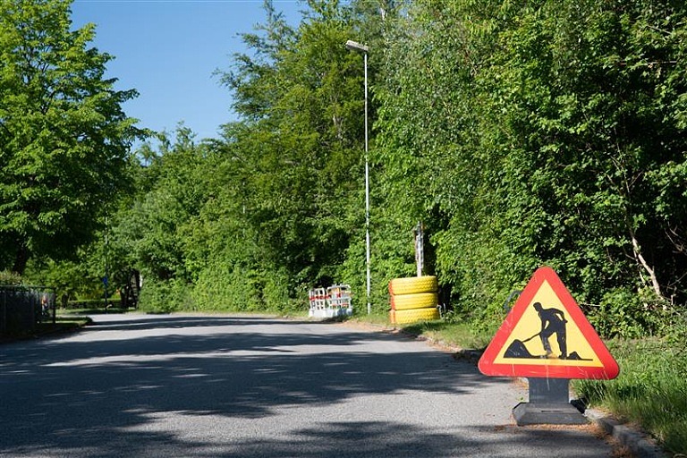 Gata, träd, vägarbetsskylt, lyktstolpe.