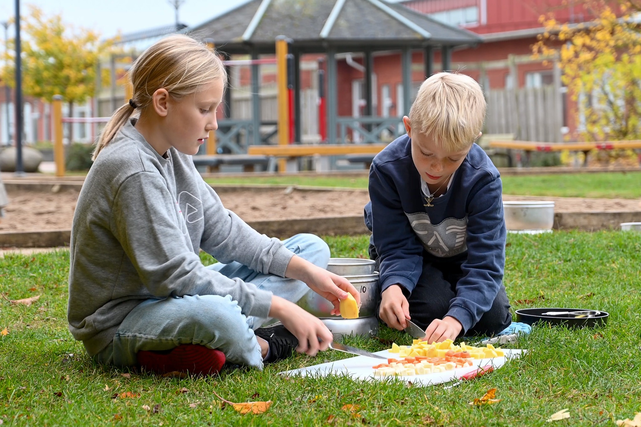 två barn på en gräsmatta som fixar med mat.