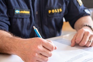 Polis sitter med penna och papper.