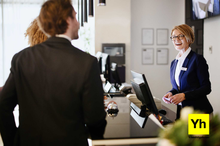 n kvinna i en hotellreception som hjälper ett par